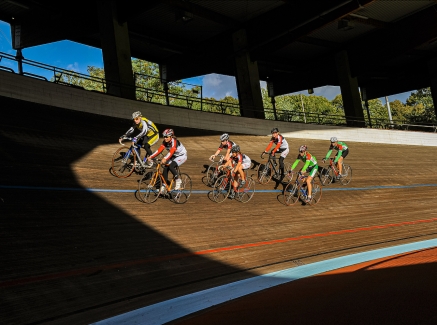 Sieben Rennradsportler fahren mit ihren Rennrädern auf der Radrennbahn des Kölner Radstadions im Sportpark Müngersdorf.