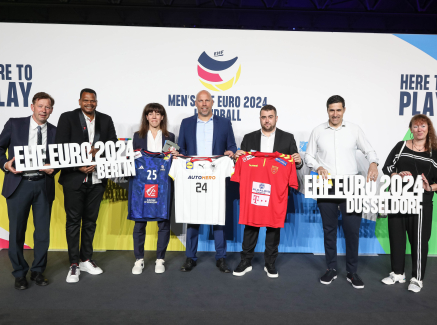 Menschen vor Sponsorenwand der EHF EURO 2024