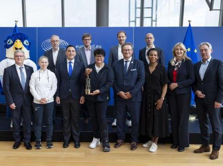 Vertreter der Staatskanzlei NRW im EU-Parlament mit Maskottchen der Rhine-Ruhr 2025