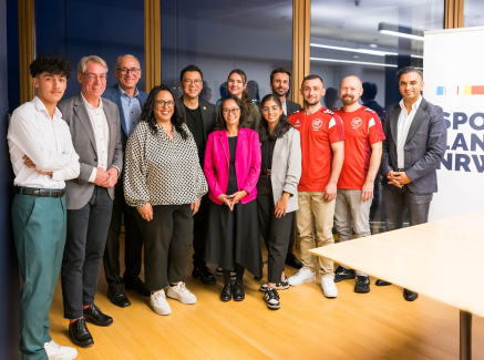 Gruppe von Personen neben einem Sportland.NRW-Banner