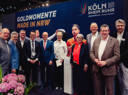 Viele Personen vor einer Wand mit Schriftzug "Goldene Momente" der KölnRheinRuhr-Bewerbung