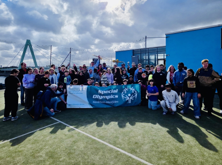 Gruppe von Kindern und Schulkindern auf einem Ballfeld vor blaumen Himmel