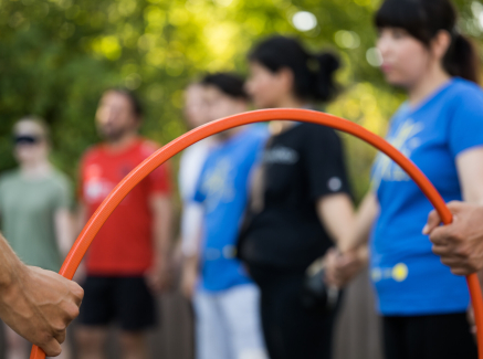 Junge Menschen, im Vordergrund ein roter Reifen, der von zwei Händen gehalten wird