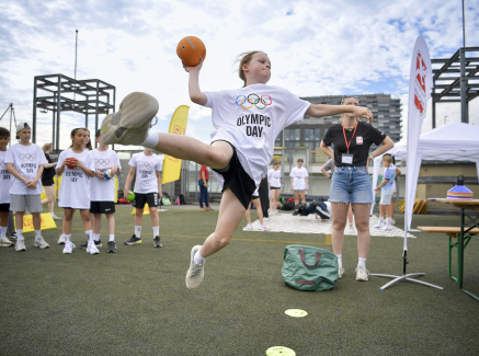 Junge Frau fliegt in der Luft und wirft einen Handball