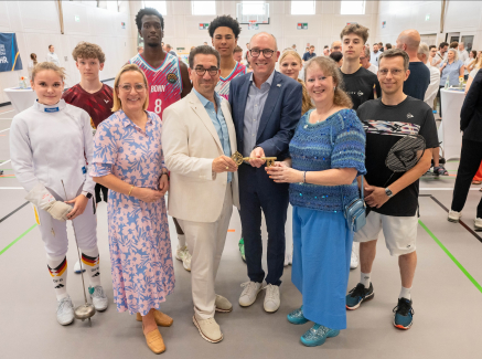 Viele Personen in einem Innenraum mit Andrea Milz in blauer Kleidung