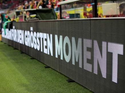 Auf einer Bande am Fußballball-Spielfeldrand steht "für den größten Moment"
