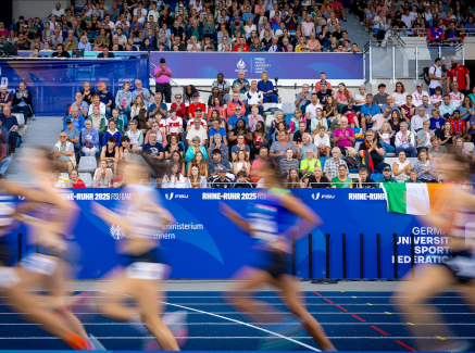 Leichtathletinnen laufen in einem Stadion vor einer vollen Zuschauertribüne