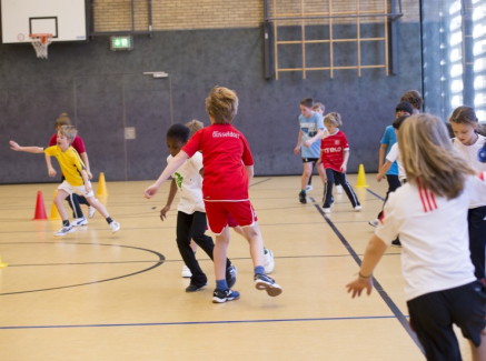 Viele Kinder spielen in einer Sporthalle miteinander