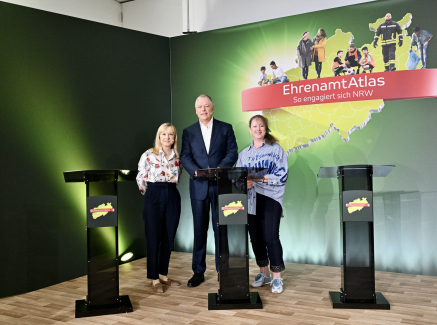 Zwei Frauen und ein Mann stehen hinter Rednerpulden