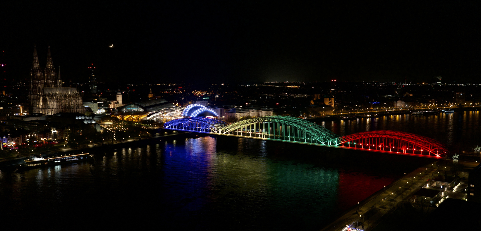 Bunt erleuchtete Brücke vor der Skyline von Köln