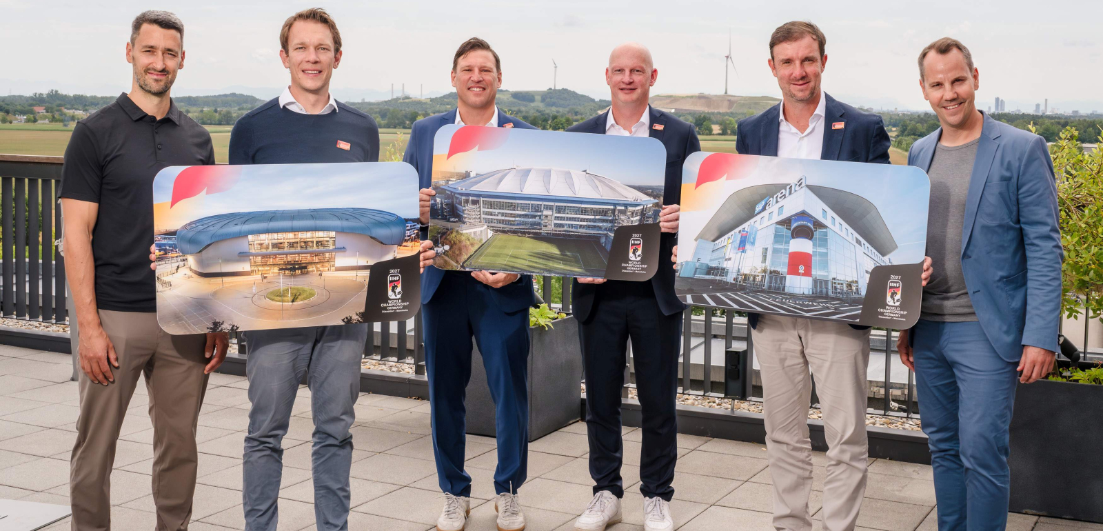 Sechs Manner auf einem Dach halten Schilder zur Eishockey-WM 2027
