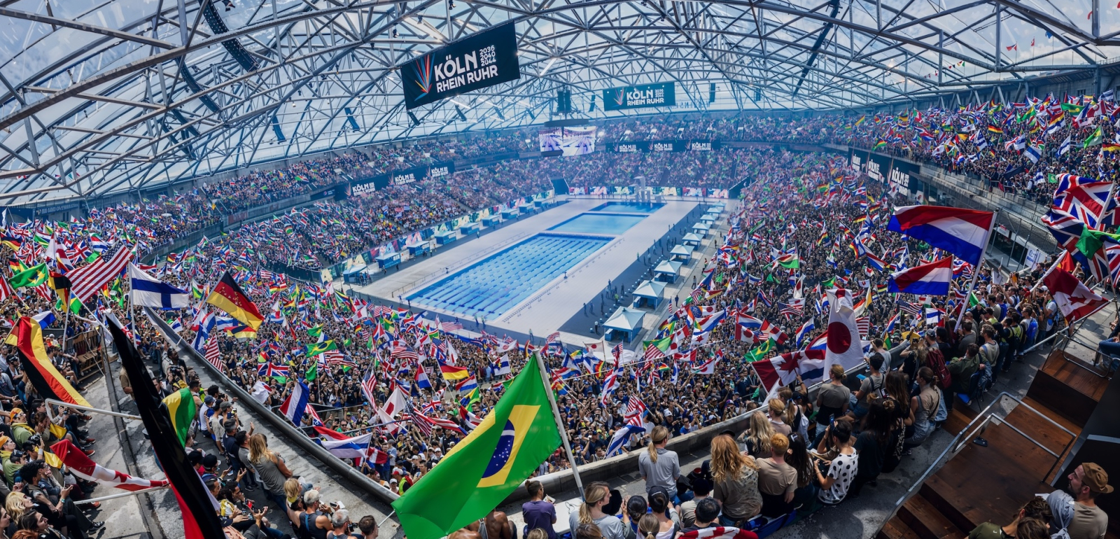 KI-Bild der Veltins Arena bei Olympischen Spielen mit einem Schwimmbecken in der Mitte und Fans drumherum