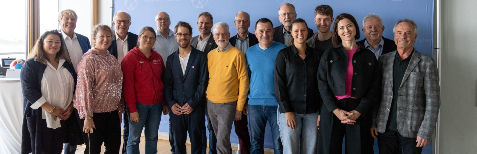 Mehrere Menschen vor einem Banner des Landes NRW