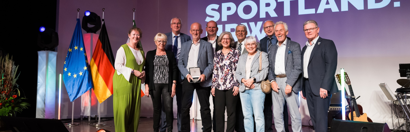 Andrea Milz mit weiteren Personen vor Sportland.NRW-Banner