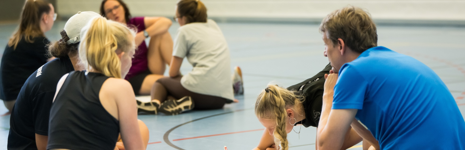 Junge Menschen in einer Sportalle beugen sich über ein Papier