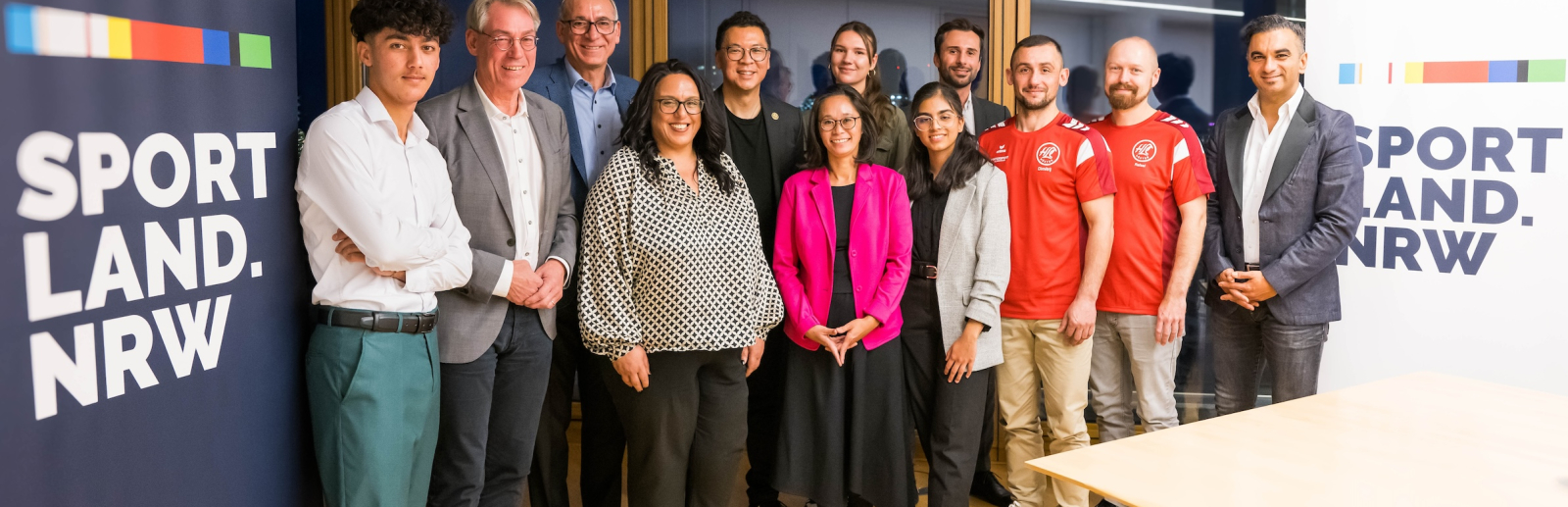 Gruppe von Personen neben einem Sportland.NRW-Banner