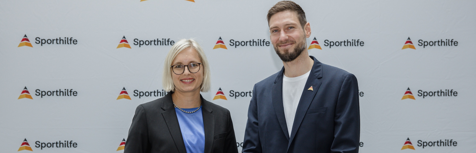 Dr. Christiane Schenderlin und Max Hartung vor einem Sporthilfe-Screen