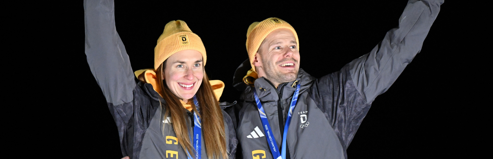 Jacqueline Pfeifer und Christopher Grotheer mit Medaillen um den Hals vor dunklem Hintergrund