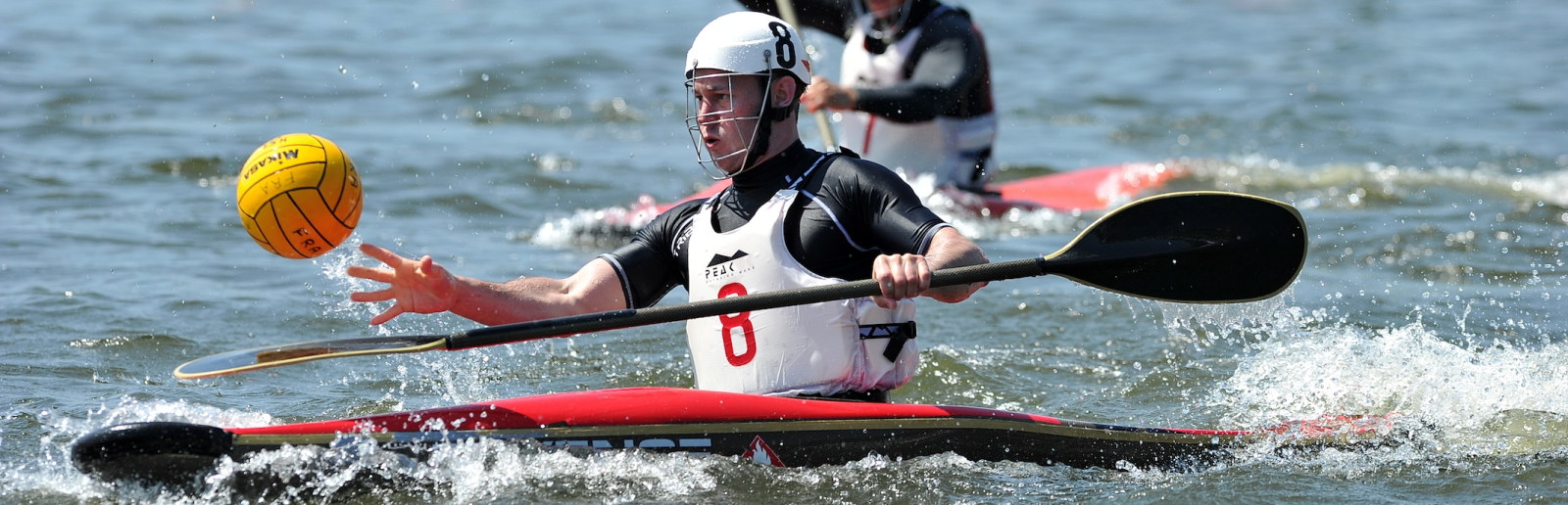 Kanu-Polo-Spieler auf dem Wasser kämpfen um einen gelben Ball