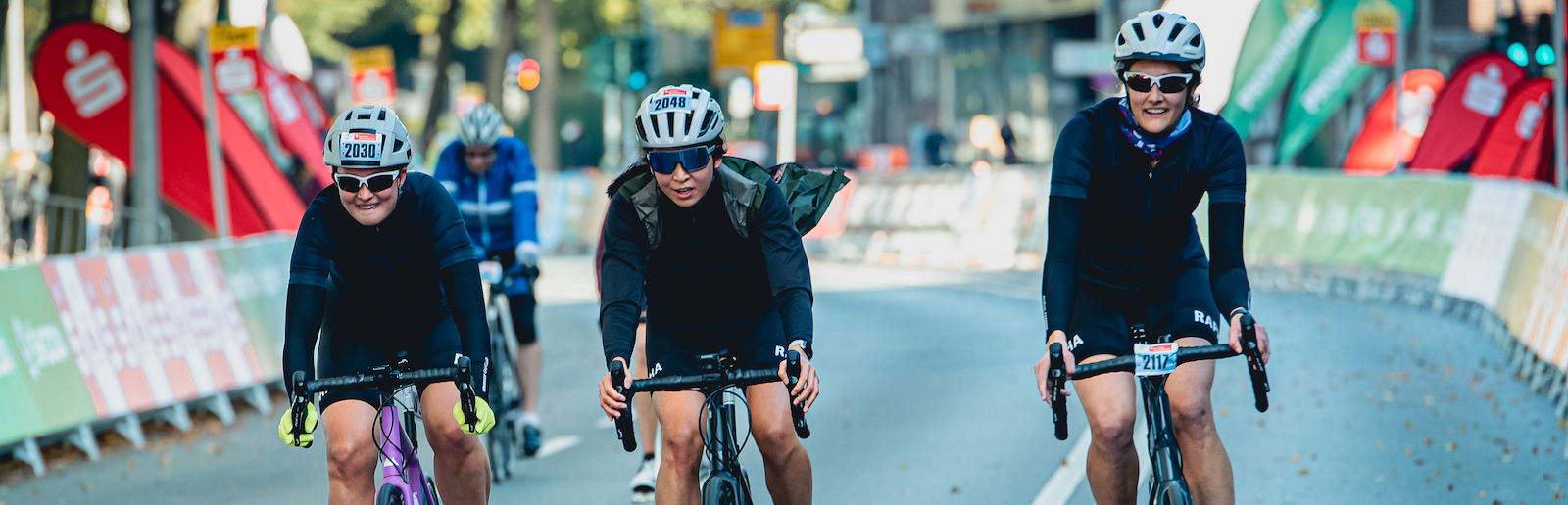 Drei Radsportler fahren nebeneinander auf der Straße