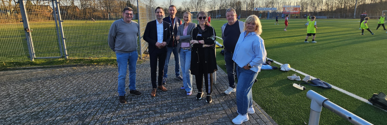 Andrea Milz mit weiteren Personen auf einem Sportplatz bei Sonnenschein und blauem Himmel