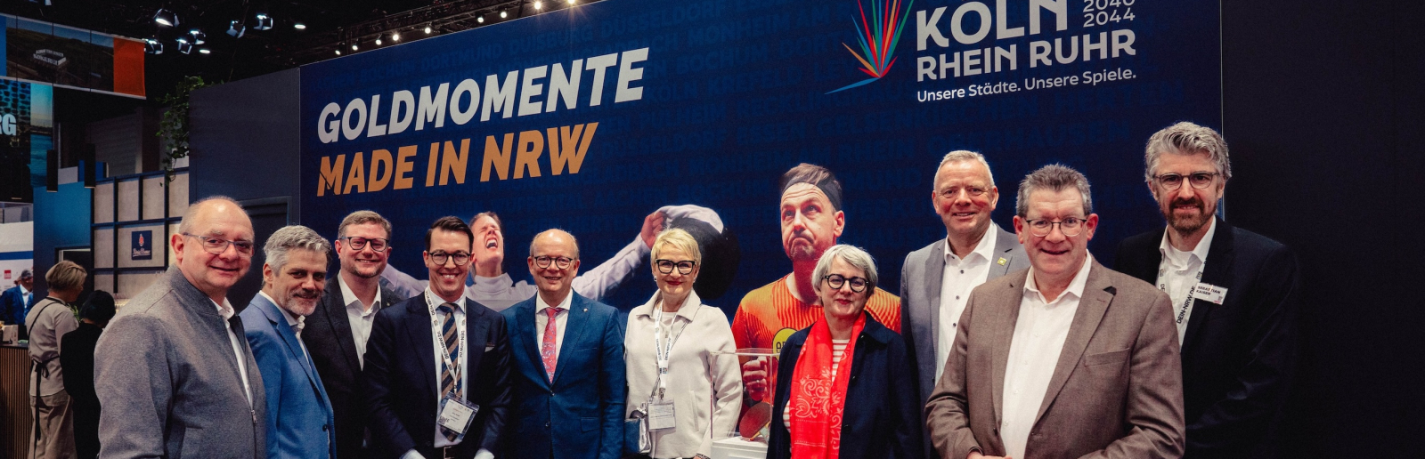 Viele Personen vor einer Wand mit Schriftzug "Goldene Momente" der KölnRheinRuhr-Bewerbung