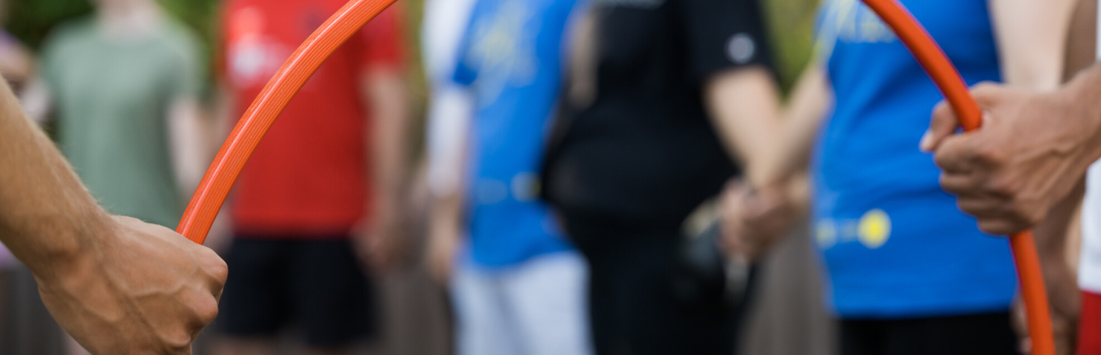 Junge Menschen, im Vordergrund ein roter Reifen, der von zwei Händen gehalten wird