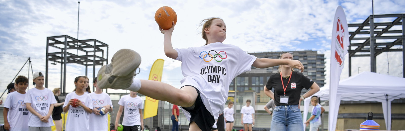 Junge Frau fliegt in der Luft und wirft einen Handball