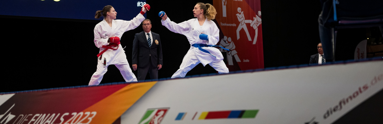 Zwei Karateka in Aktion, im Vordergrund ein Schild mit "Sportland.NRW"