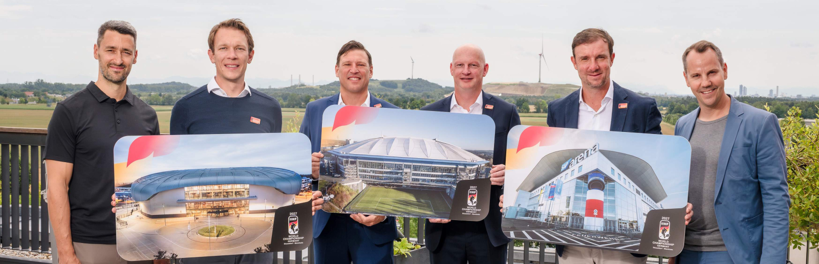 Sechs Manner auf einem Dach halten Schilder zur Eishockey-WM 2027
