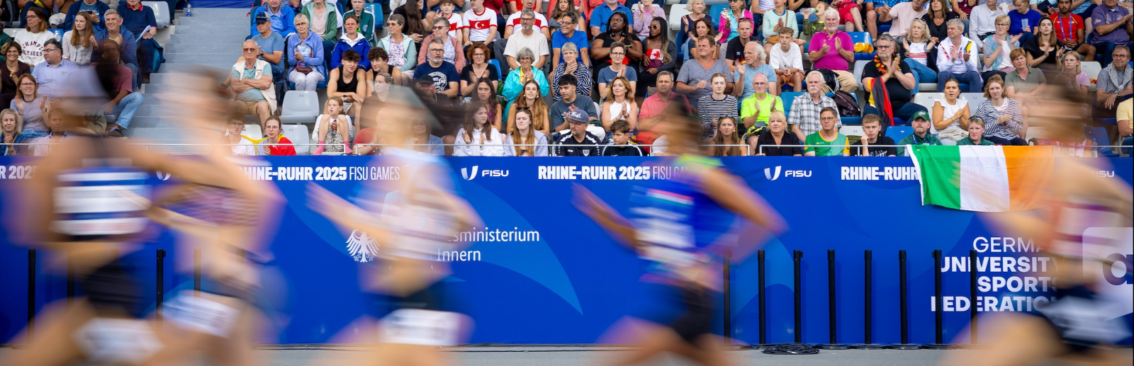 Leichtathletinnen laufen in einem Stadion vor einer vollen Zuschauertribüne
