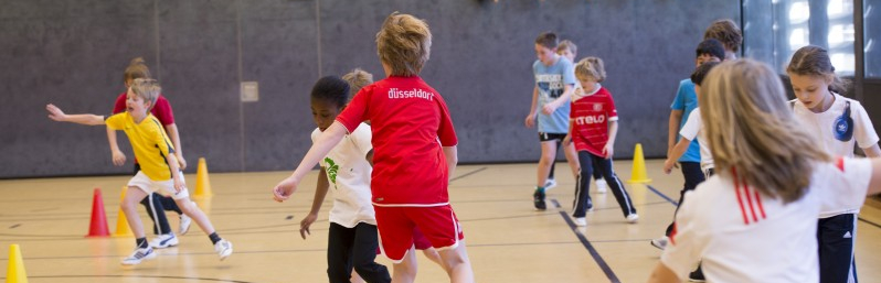 Viele Kinder spielen in einer Sporthalle miteinander