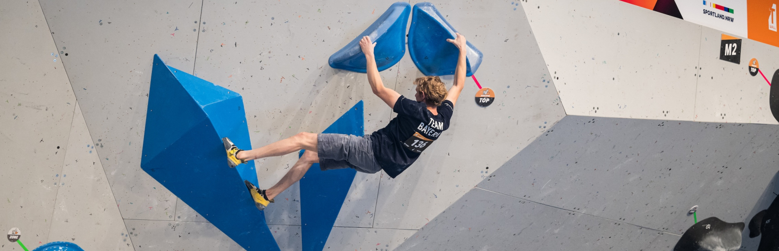 Athlet in schwarzem Shirt an einer Kletterwand bei den Finals