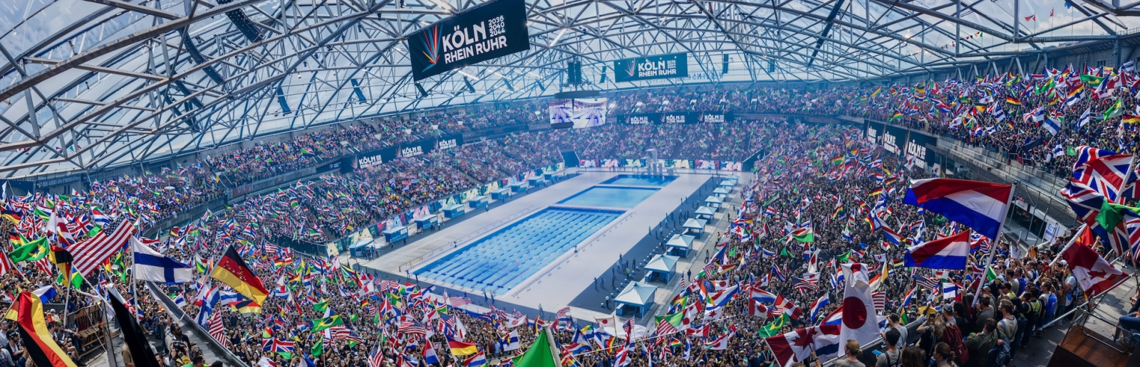 KI-Bild der Veltins Arena bei Olympischen Spielen mit einem Schwimmbecken in der Mitte und Fans drumherum