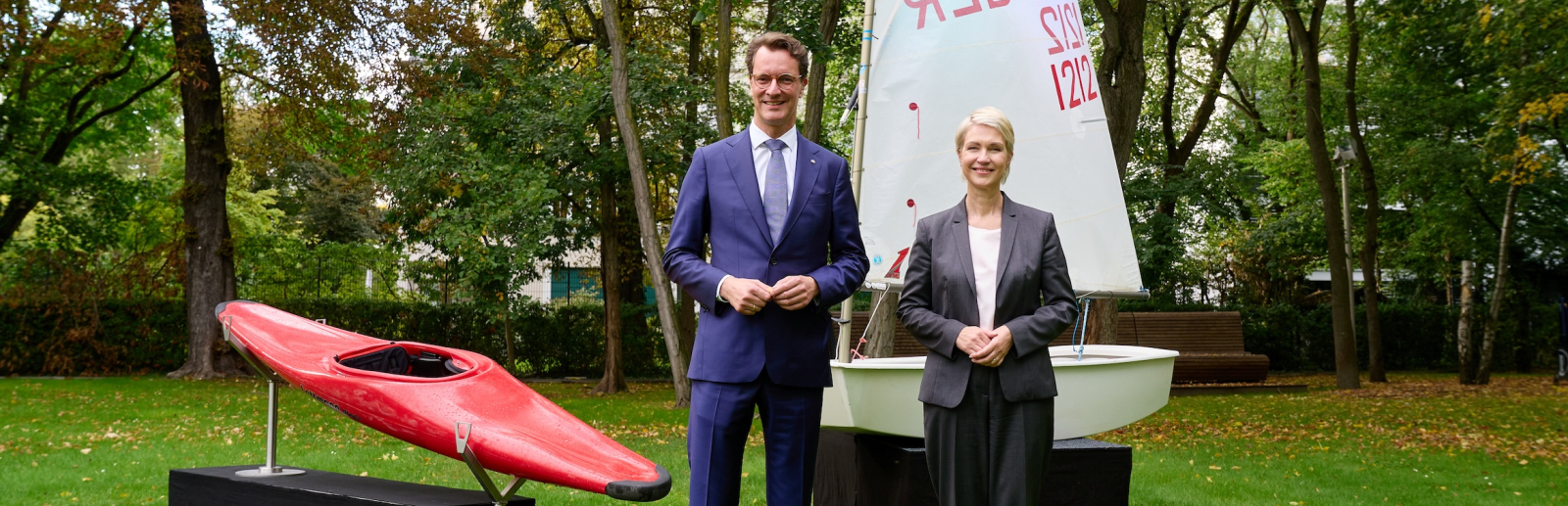 Ministerpräsidenten Schwesig und Wüst mit einem Kanu und einem Segelboot im Hintergrund