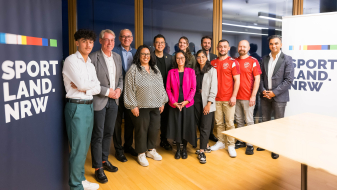 Gruppe von Personen neben einem Sportland.NRW-Banner
