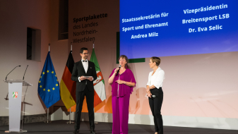 Bühne mit Redner, Andrea Milz und Eva Selic 