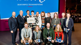 Mehrere Personen in zwei Reihen hintereinander vor einem großen blauen Banner mit 45.500 Euro