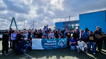 Gruppe von Kindern und Schulkindern auf einem Ballfeld vor blaumen Himmel