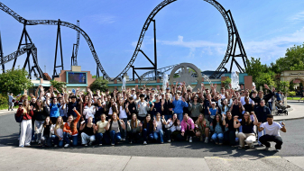 Gruppe von Menschen vor einer Achterbahn