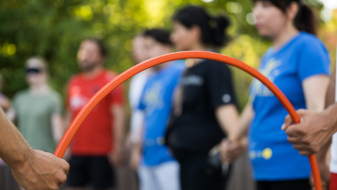 Junge Menschen, im Vordergrund ein roter Reifen, der von zwei Händen gehalten wird