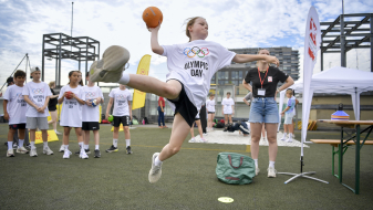 Junge Frau fliegt in der Luft und wirft einen Handball