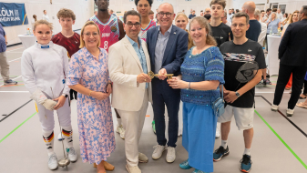 Viele Personen in einem Innenraum mit Andrea Milz in blauer Kleidung