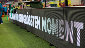 Auf einer Bande am Fußballball-Spielfeldrand steht "für den größten Moment"