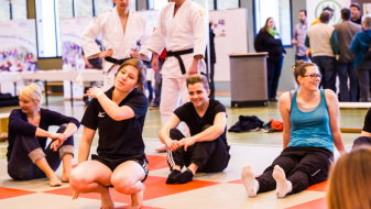 Gruppe von jungen Frauen und Männern in einer Sporthalle, einige in Judo-Dress