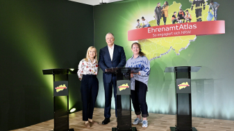 Zwei Frauen und ein Mann stehen hinter Rednerpulden