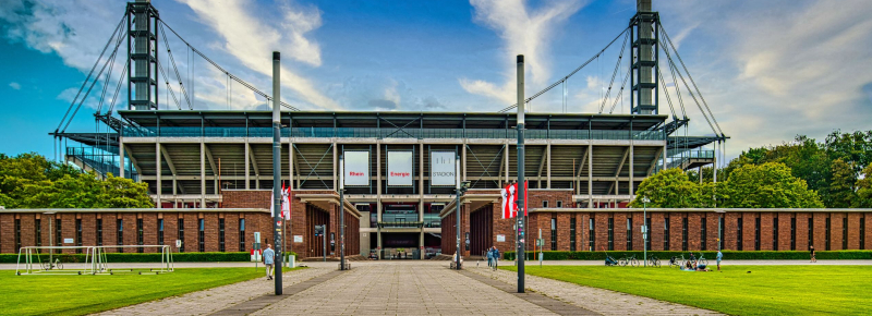Rheinenergiestadion von außen mit Wiese im Vordergrund