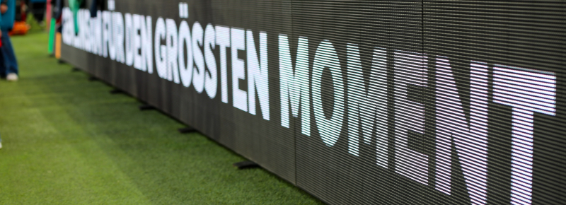 Dunkle Bande im Fußballstadion mit der Aufschrift "Für den größten Moment"