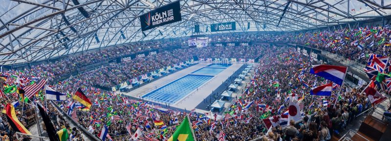 KI-Bild der Veltins Arena bei Olympischen Spielen mit einem Schwimmbecken in der Mitte und Fans drumherum
