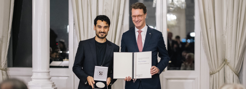 Ministerpräsident Wüst und Ilkay Gündogan mit Medaille und Auszeichnung